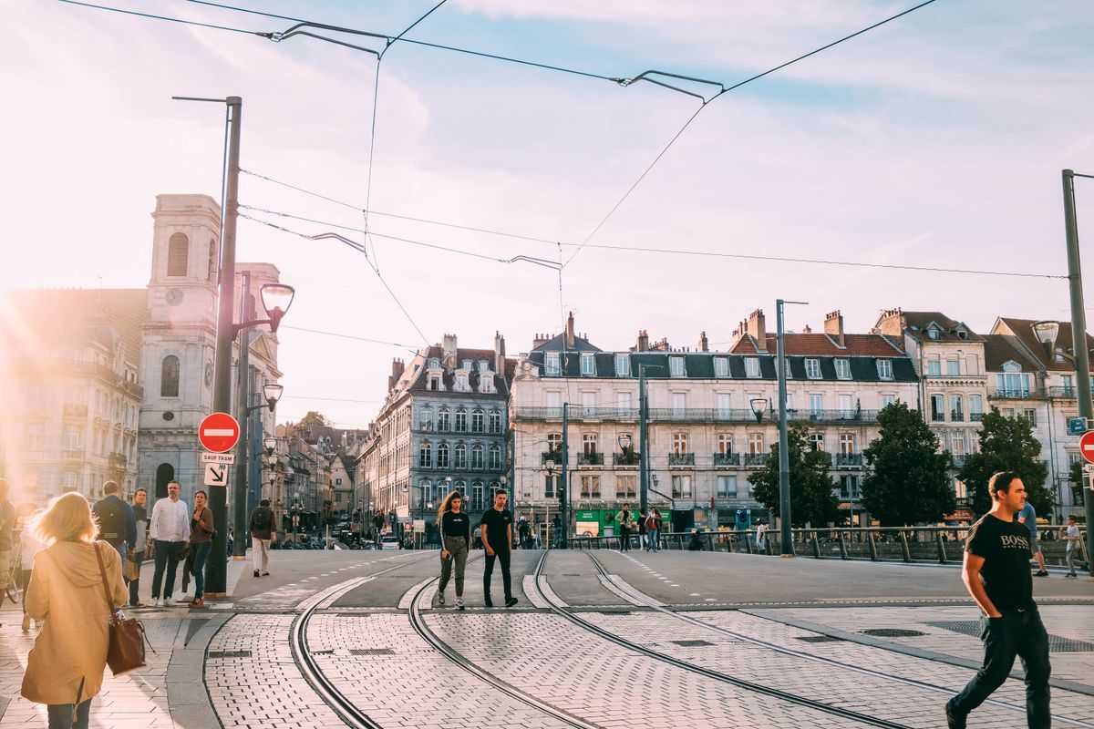 Skrzyżowanie z torami tramwajowymi w złotym świetle, przechodnie w ruchu — scena z warsztatu ulicznego