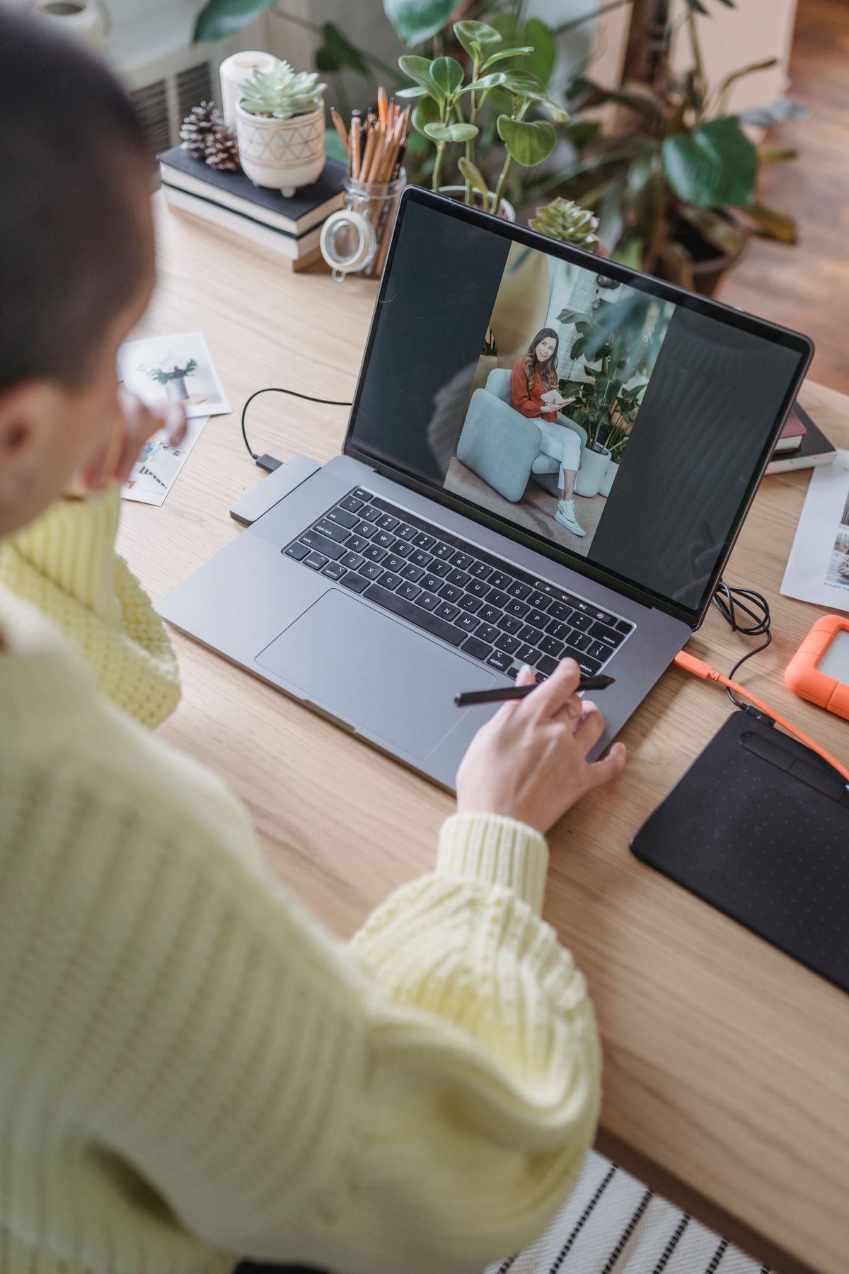 Fotografka selekcjonująca zdjęcia na laptopie z tabletem graficznym na biurku