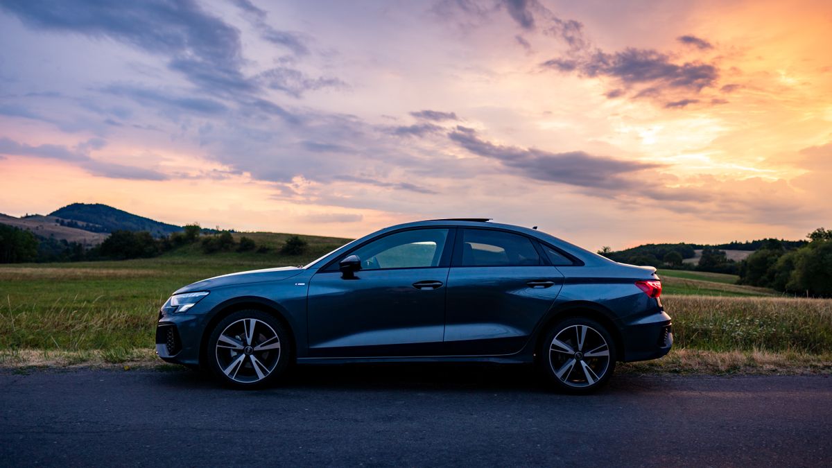 Ciemnoszary sedan Audi A3 w profilu o zachodzie słońca