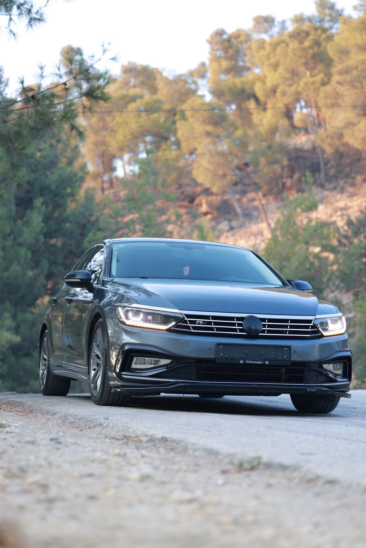 Grafitowy Volkswagen Passat B8 na drogę gruntową w twardeym świetle dnia