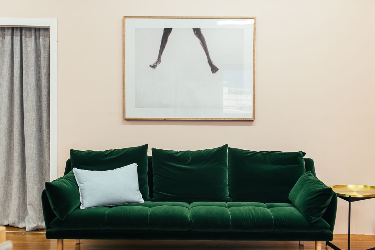Zielona aksamitna sofa przy różowej ścianie — detal z sesji wnętrzarskiej