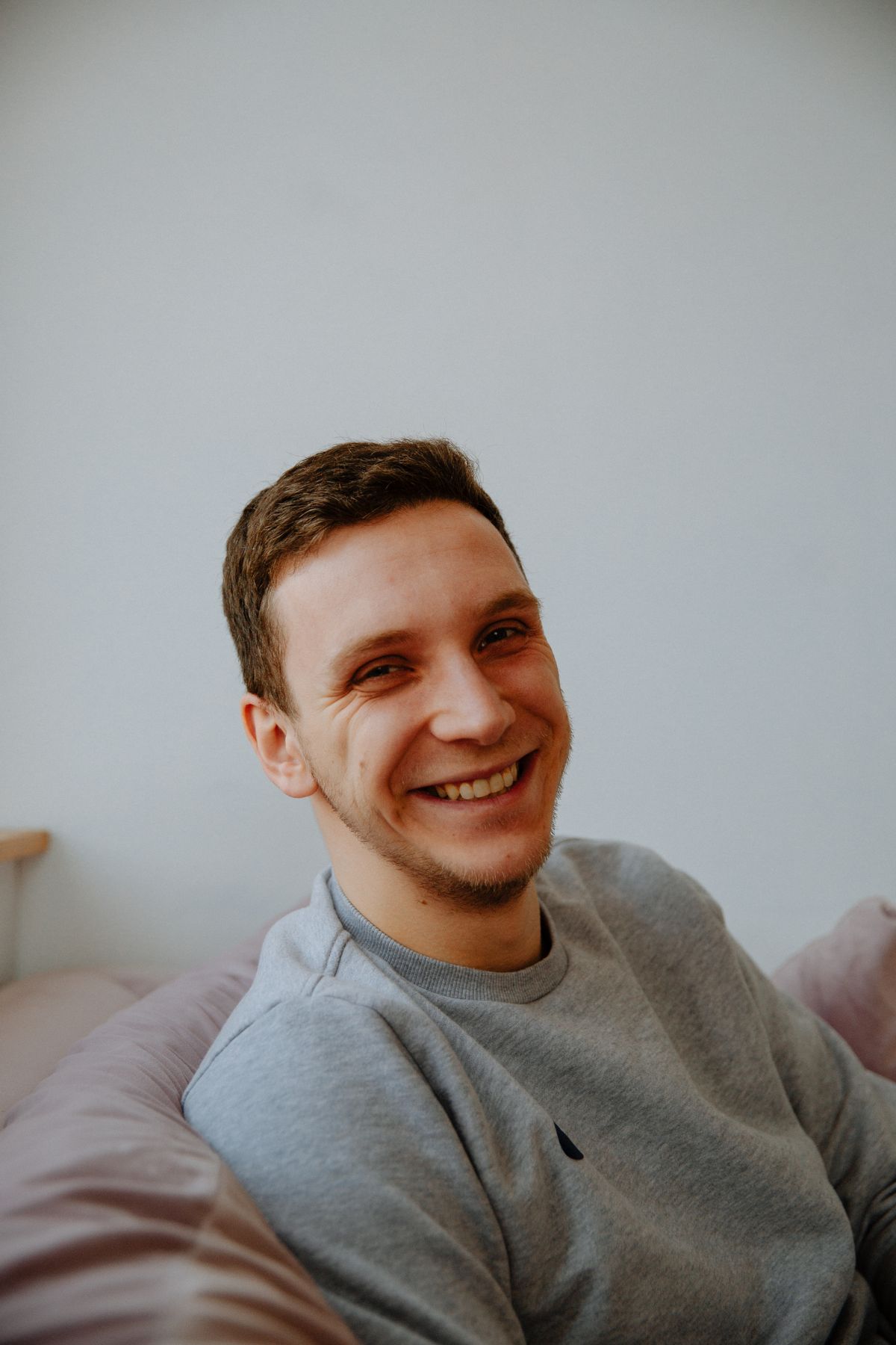 Portret uśmiechniętego mężczyzny w swetrze, w jasnym wnętrzu