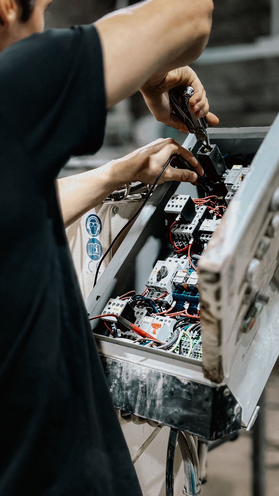 Elektryk zaciskający przewody w otwartej rozdzielnicy elektrycznej